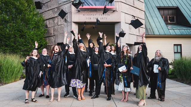 Language School graduates celebrate by throwing their caps in the air 