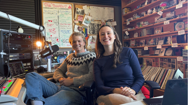Two students sitting in radio studio smile to camera