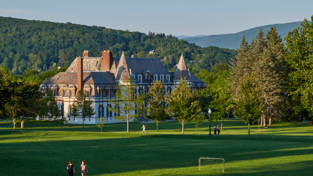A summer photo of Middlebury College's Le Chateau building with mountains in the background