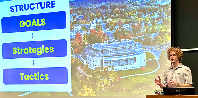 A student gives a presentation at a lectern in a classroom.