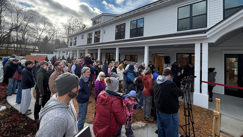 A crowd gathers outside a white building.