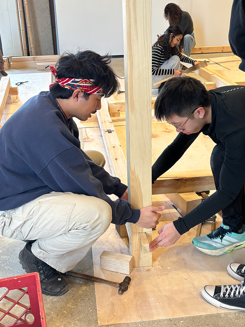 Students assemble a timberframe structure in a studio