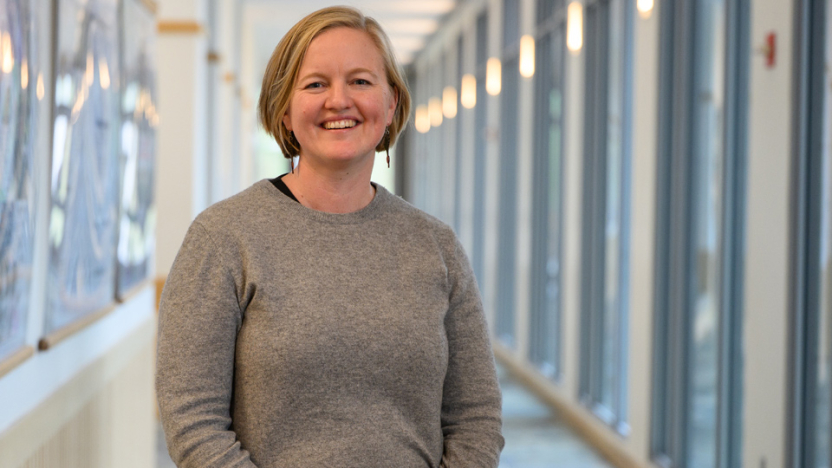 Person in gray sweater smiles at the camera.
