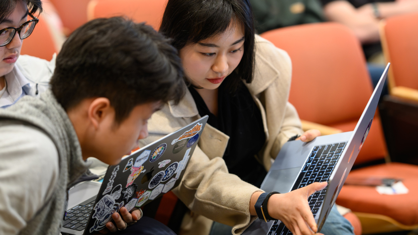 Two students focus on a laptop in preparation for a presentation.