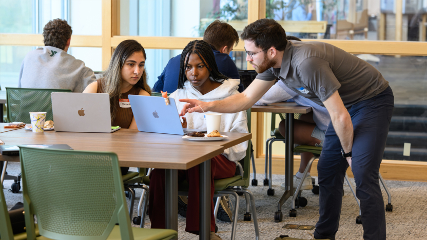 Students and a professor focus on a laptop screen.