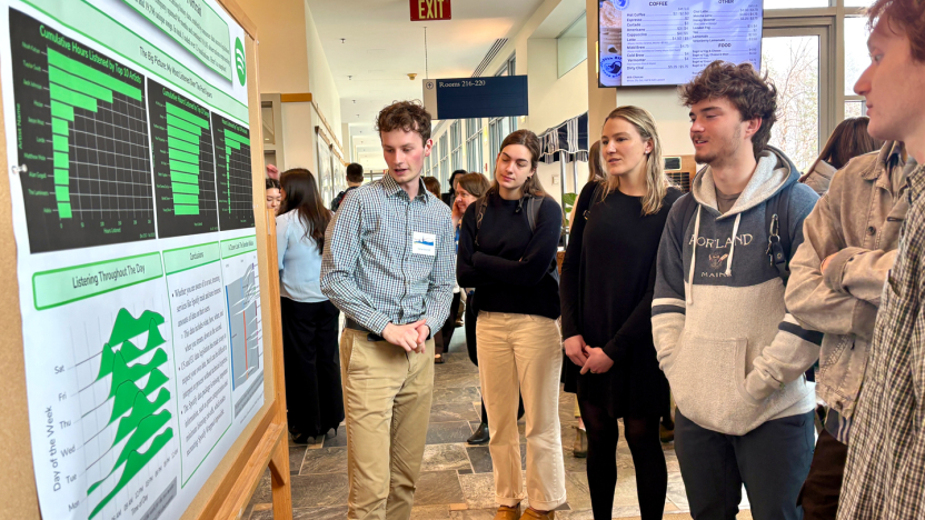 A student presents research findings during a poster session.