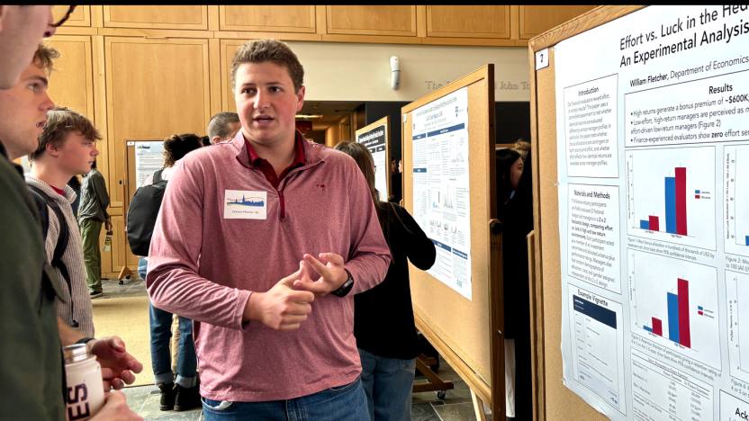 A student presents research findings during a poster session.