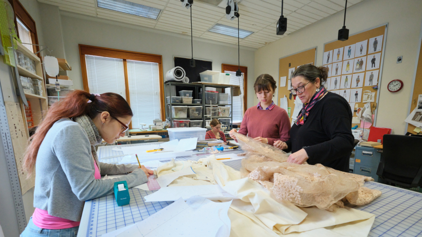 Students and staff work together at a table in the costume shop.