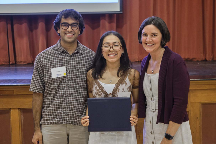 Three people pose for a photo during an awards ceremony.
