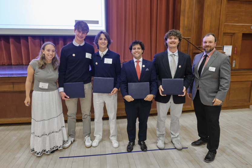 A group of students and staff members pose for a photo at an awards ceremony.