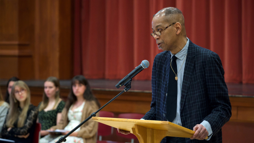 A person wearing a dark blazer speaks at a podium.