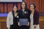 Three people pose for a photo during an awards ceremony.