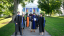 Professors and administrators in academic regalia smile for a group photo outside Middlebury Chapel.
