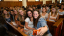 Students in chapel pews take a group selfie surrounded by smiling classmates.