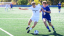 A man in a Middlebury uniform kicks a soccer ball. He is pushing away an opposing player. 