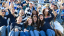 A group of spectators cheers from the bleacher seating at the Middlebury football stadium