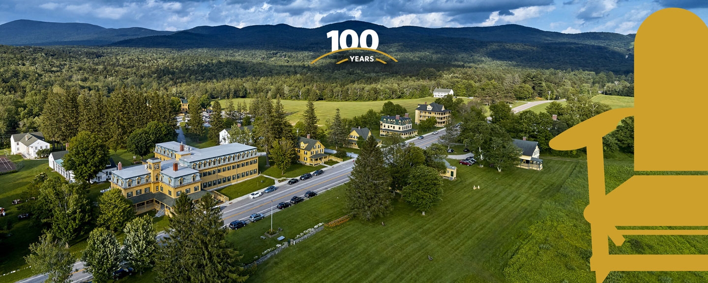 Aerial view of the Bread Loaf campus with 100 years and an illustration of a yellow Adirondack chair.