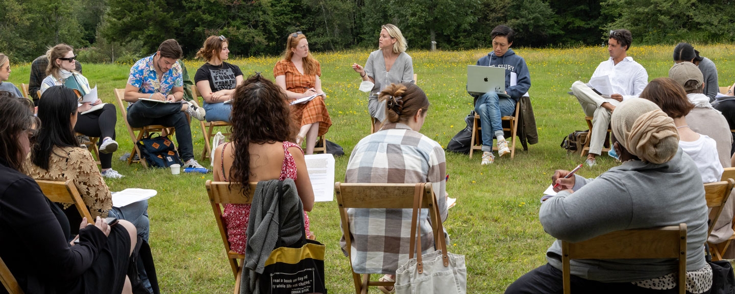 A group of participants in the Bread Loaf Writers’ Conference are gathered outdoors on chairs for a workshop discussion.