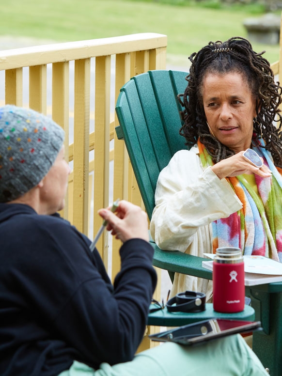 Faculty member Carolyn Finney and a student discuss a manuscript while sitting on the Front Porch of the Bread Loaf Inn.